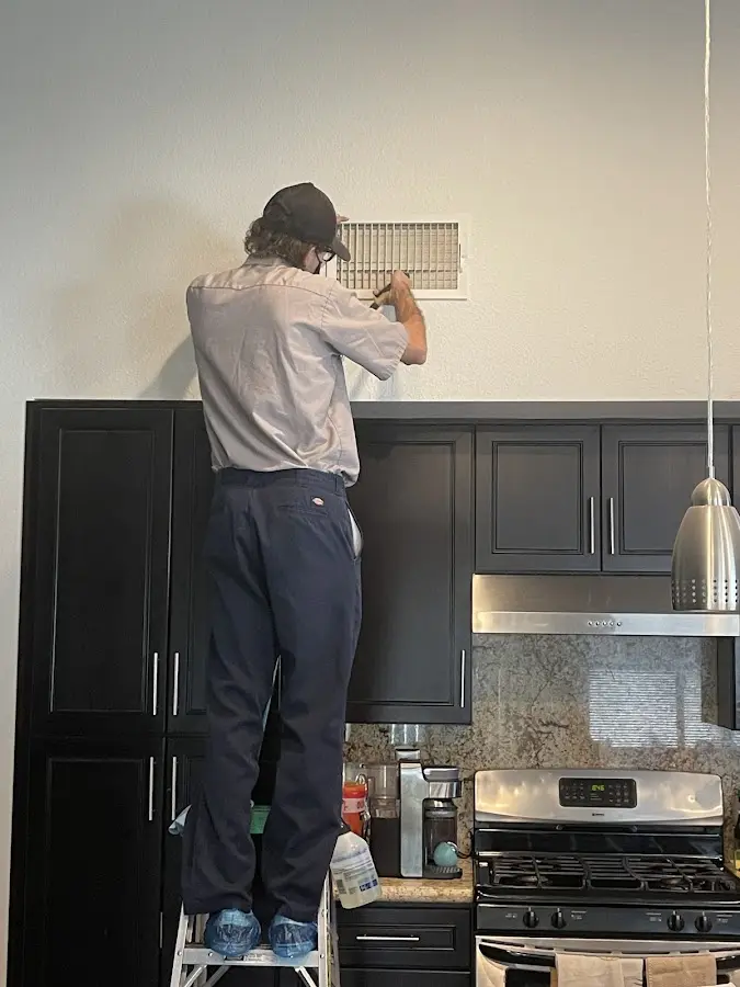 Technician inspecting an air vent during HVAC service in Gun Plain